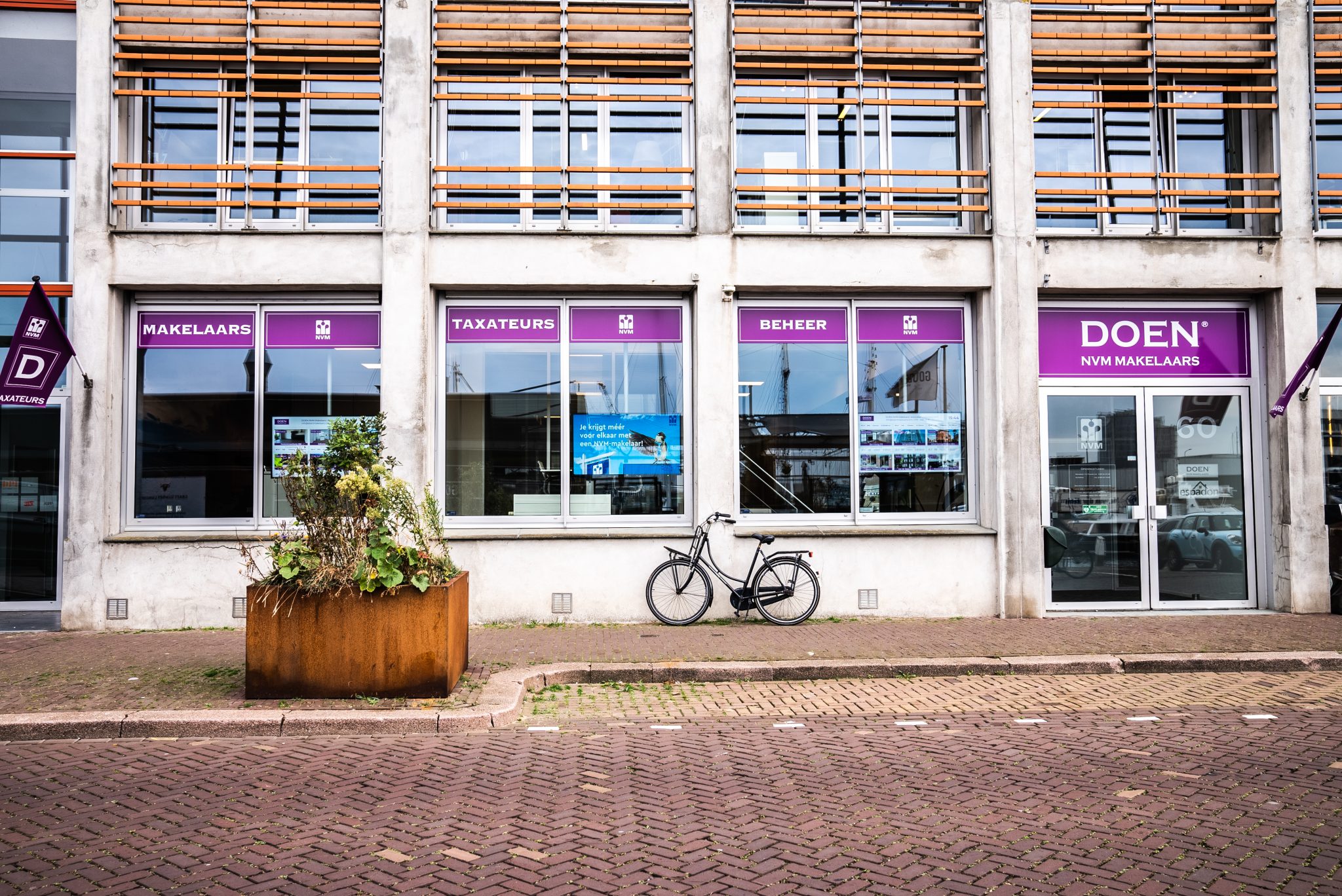 Narrowcasting scherm in etalage van makelaarskantoor toont digitale content en woningaanbod.